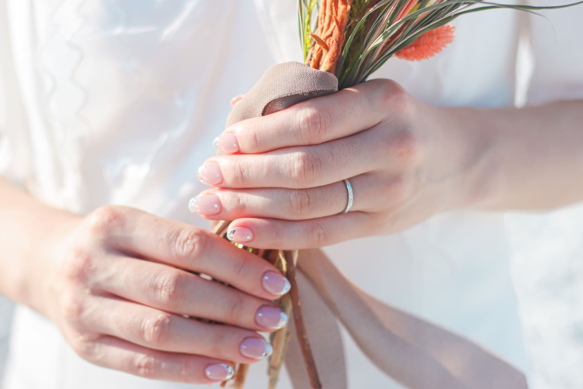 結婚指輪を着けてブーケを持つ手元